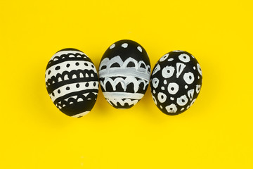 top view collection of dyed black and white easter eggs on a yellow background