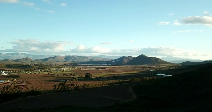 View overlooking a rural village and farmland in South Africa with mountains in the background slow pan left