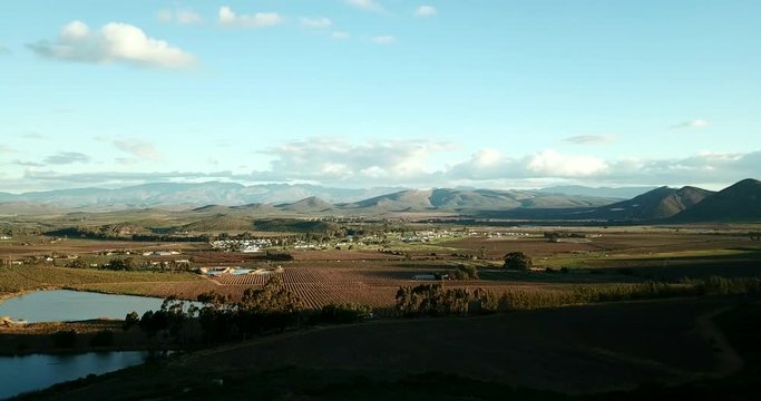Overlooking a valley with farmland and a rural town in South Africa with dams in the foreground slow pan left