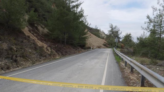 Yellow police tape blocks off a mountain road after a landslide.