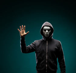 Computer hacker in white mask and hoodie. Obscured dark face. Data thief, internet fraud, darknet...