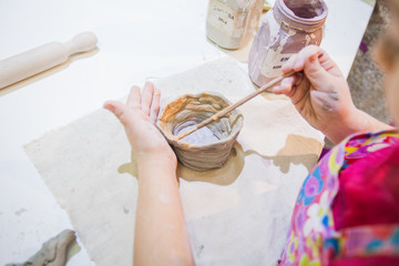 childrens hands painting with brush self-made clay items