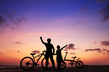 Silhouette of stepmother alone with children and bicycle at sunset so strong