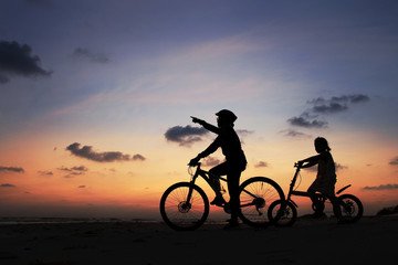 Fototapeta na wymiar Silhouette of stepmother alone with children and bicycle at sunset