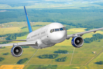 Airplane flies gaining height against the background of the landscape earth's surface