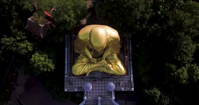 Aerial top down shot of a huge golden buddha monument in Thailand. FLY UP