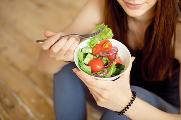 Close-up young caucasian woman eating fresh vegetable salad