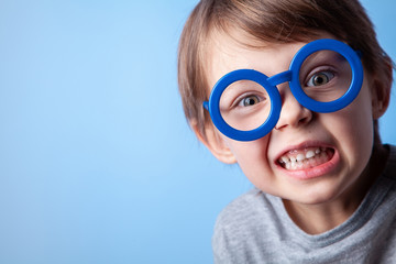  Cute baby in blue glasses on a blue background in the studio.