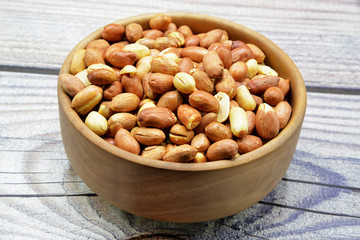 peanuts in bowl on wooden background