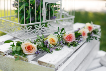 Festive rustic style decorations fresh flowers and white birdcage on a wooden box. Sunny summer day