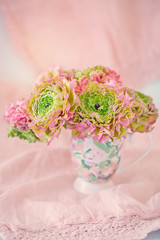 A beautiful bouquet of spring flowers on a pink background on the table with a tablecloth. Pastel colors.