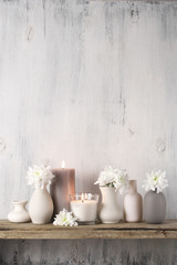 Fototapeta na wymiar White flowers in neutral colored vases and candles