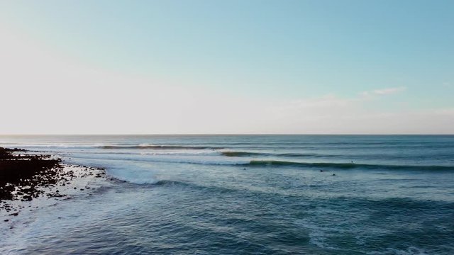 Aerial Drone Shot Flying Over Water With People Surfing Curling Waves In Ocean In Raglan New Zealand