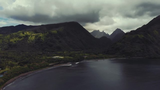 Dramatic panorama aerial view of black sand beach and a valley with mountains near Tautira village, Tahiti Iti island, French Polynesia, south Pacific ocean.