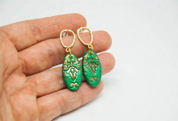 Bohemian bright gold and green stud earrings in woman hand. Handmade oriental jewelry.