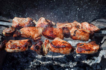 Pieces of grilled pork with red crust  on brazier over the coals