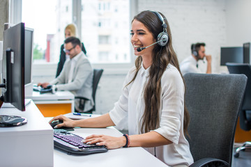 Portrait of young attractive happy smiling female customer support phone operator at modern office