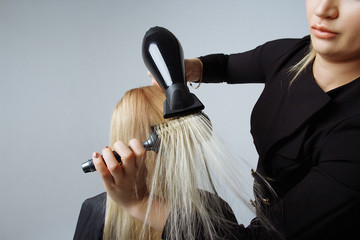 Naklejka premium portrait of a girl Hairdresser dries hair with a hairdryer in beauty salon