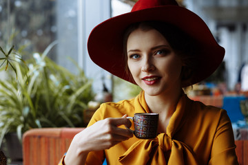 portrait of a girl in a cafe with a cup of coffee and a hat.portrait of sensual young girl wearing...