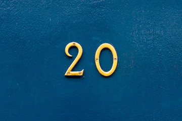 House number 20 in bronze numerals on a blue painted wall