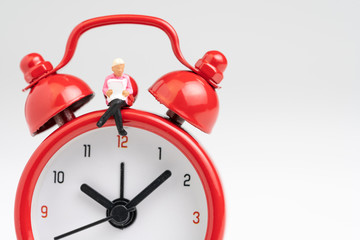 Business deadline, timer or time counting down concept, miniature office lady secretary holding document sitting on red alarm clock on white background with copy space