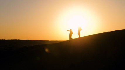 Two male silhouettes in desert
