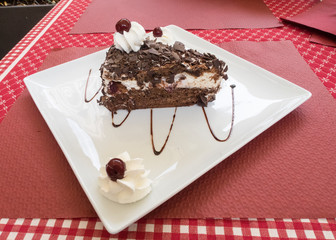 Slice of black forest cake on a white plate on a table
