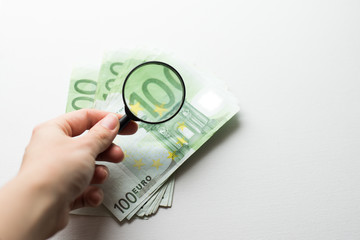 Hundred euro banknote under magnifying glass isolated on white background