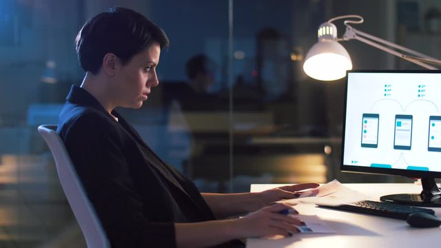 business, technology and people concept - ui designer with smartphone templates on computer screen working on user interface design at dark night office