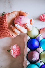 The girl is holding a pink easter egg on a stand, pink and marble background, minimalism, flowers
