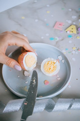 Girl cutting golden easter eggs on marble background, confetti, sparkles, ribbons.