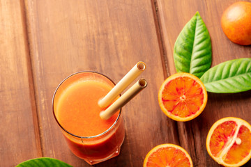 A closeup of reusable bamboo straws in a glass of vibrant orange juice, with copy space. Selective...