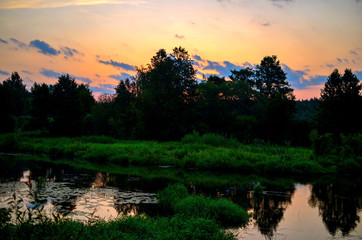Beautiful summer landscape with sunrise in the morning on the river "Bobr", Belarusian nature. Colorful misty sunrise on a small river. Cut away thick green grass and trees. © MaxSafaniuk
