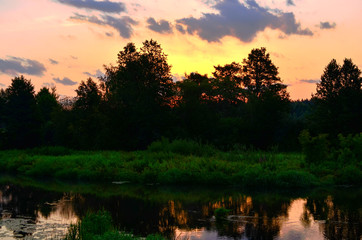 Beautiful summer landscape with sunrise in the morning on the river "Bobr", Belarusian nature. Colorful misty sunrise on a small river. Cut away thick green grass and trees. © MaxSafaniuk