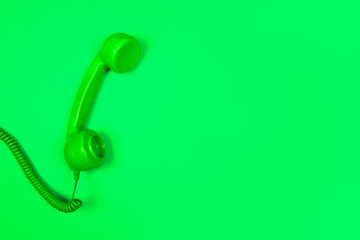 Neon green retro telephone on a green background with copy space