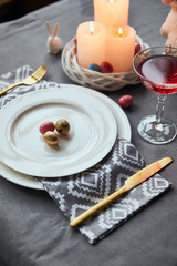 Selective focus of plates with cloth napkin, eggs in basket, wine in crystal glass on table at home