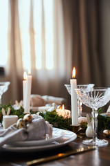 selective focus of burning candles near plates, moss and crystal glasses on wooden table at home