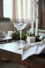 selective focus of crystal glasses near green moss and candles on wooden table at home