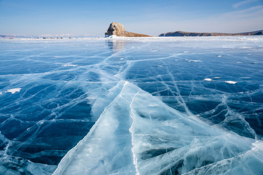 Baikal lake in winter day. Cracks on surface of the natural ice in frozen water behind the cliffs of Olkhon Island at Baikal lake, Russia