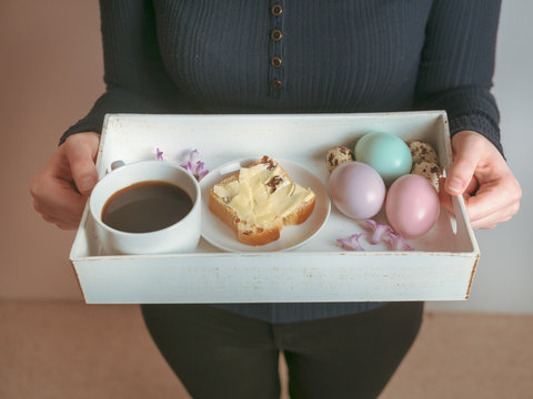 Osterbruch auf einem Serviertablett in den Händen einer jungen Frau, Ostern, Kaffee, Frühstück