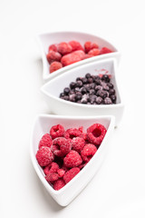 fresh berries in white shaped bowls isolated on white