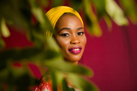 Portrait of a lady wearing yellow scarf on red background with some blurred flowers in the foreground. 