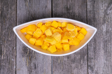 fresh cutted mango in a shaped bowl on wooden table