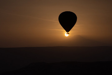 Hot air balloons flying over spectacular Cappadocia on sunset.