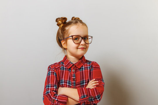 Portrait of a funny little preschool child girl in glasses on gray background. Education. Back to school.