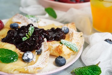 French crepes with blueberry compote topping, selective focus