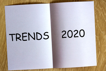 White sheen of paper on wooden background with text "Trends 2020" on it.