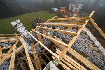 Top view of roof frame from wooden lumber beams and planks on walls made of hollow foam insulation blocks. Building, roofing, construction and renovation concept.