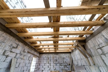 House room interior under construction and renovation. Energy saving walls of hollow foam insulation blocks, wooden ceiling beams and roof frame.