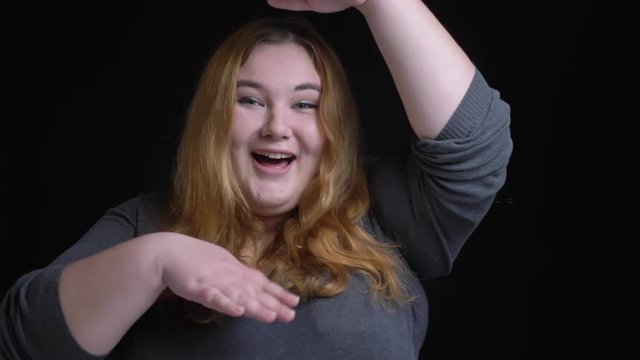 Closeup shoot of young overweight caucasian female dancing and laughing cheerfully in front of the camera